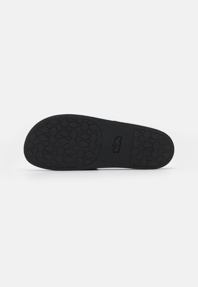 Black rubber shoe sole with a textured surface featuring a pattern of oval shapes for grip, flat design, and minimalistic detailing.