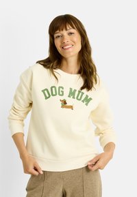 Sudadera color crema con el texto "DOG MUM" en verde y un dachshund bordado con bufanda. Material suave con puños acanalados.