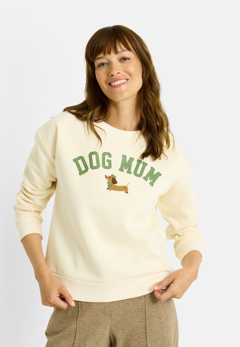 Sudadera color crema con el texto "DOG MUM" en verde y un dachshund bordado con bufanda. Material suave con puños acanalados.