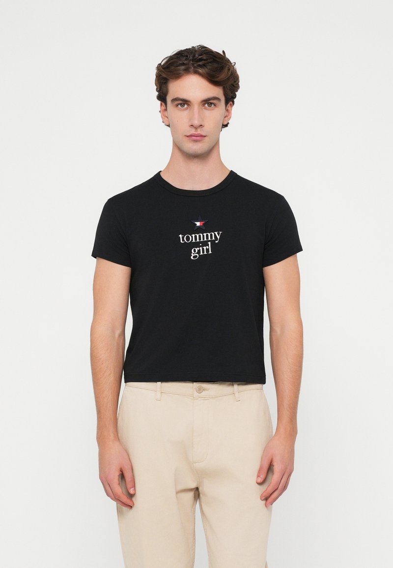 Černé bavlněné tričko s krátkým rukávem a kulatým výstřihem. V centru se nachází nápis "tommy girl" a malé hvězdné logo.