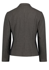 Svart och vit mönstrad kavaj med en figursydd design, spetsig krage och solida svarta sidopaneler. Långa ärmar och strukturerad tyg.