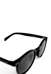 Černé sluneční brýle s lesklým povrchem. Široké, zaoblené obroučky, tmavé skla a mírně kočičí tvar. Detailní akcenty na závěsech a stranách.