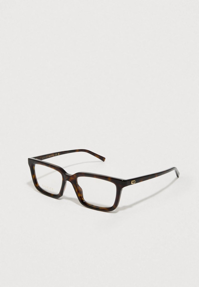 Gafas de ojo de gato de carey rectangulares con acentos dorados. Montura de plástico grueso, lentes transparentes y un sutil detalle del logo en la patilla.