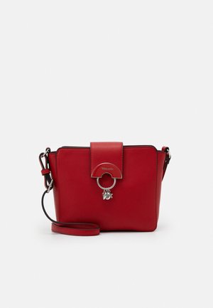 Bolso bandolera rectangular rojo con correa ajustable, cierre frontal con solapa que presenta un anillo metálico y pequeños charms colgantes.