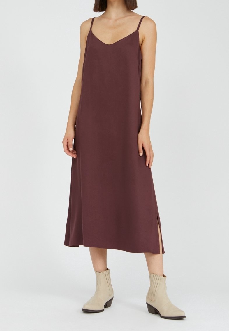 Mauve pitkähihaton maksimekko, jossa on V-pääntie, sivuaukot ja sileä kangas. Yhdistettynä kermaisiin nilkkabootseihin ja minimalistiseen muotoiluun.