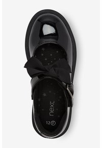 Chaussure Mary Jane en cuir verni noir avec un détail en nœud, dotée d'un bout rond, d'une sangle ajustable et d'une doublure intérieure noire à motif d'étoiles.