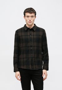 Károvaná flanelová košeľa v tmavohnedej a čiernej farbe, s dlhými rukávmi, štandardným golierom a zapínaním na gombíky vpredu. Mäkká textúra.