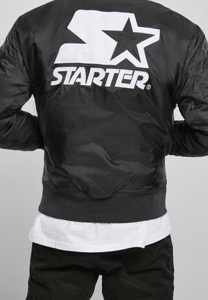 Giubbotto bomber nero con texture lucida, logo bianco oversize "STARTER" e design a stella sul retro, polsini e orlo a costine.