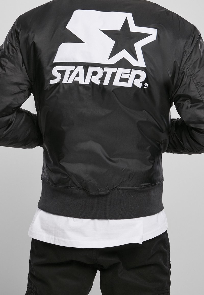 Giubbotto bomber nero con texture lucida, logo bianco oversize "STARTER" e design a stella sul retro, polsini e orlo a costine.