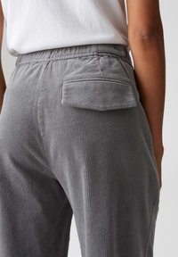 Grijze corduroy broek met verticale ribbelstructuur, voorzien van een achterzak en een elastische tailleband voor comfort.