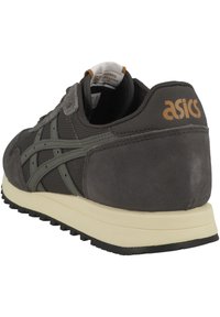 Zapatillas de malla y ante gris con una entresuela color crema, presentando una suela de goma negra y el logo de Asics en el talón.