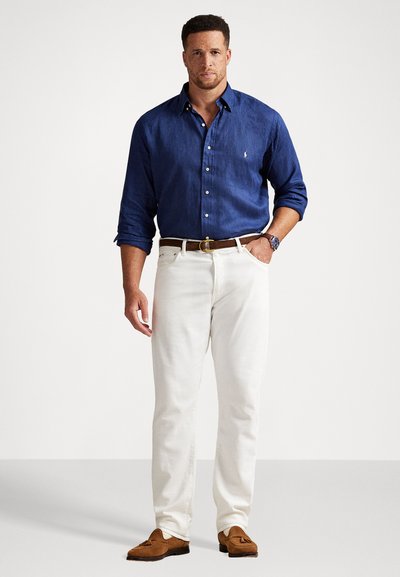 Blå långärmad skjorta med knappar, vita byxor, brun läderbälte och tan loafers. Skjortan är tillverkad av lättviktig tyg med logodetalj.