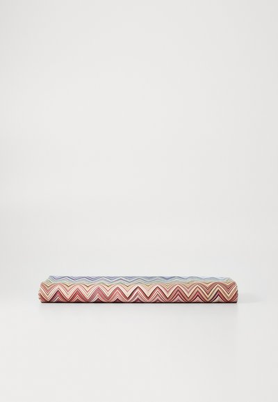 Woven fabric cushion with multicolored zigzag pattern in red, blue, and cream, featuring a rectangular shape and a smooth texture.