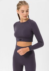 Purple long-sleeve crop top with ribbed texture and logo at the hem, paired with matching ribbed high-waisted leggings.