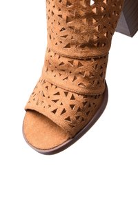 Sandal in suede tan con tacco, caratterizzata da ritagli geometrici, design con punta aperta e un solido tacco a blocco marrone per stabilità.