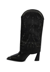 Botín negro hasta el tobillo con punta afilada y punta metálica. Presenta un corte decorativo con patrones perforados y tachuelas plateadas. Tacón ancho.
