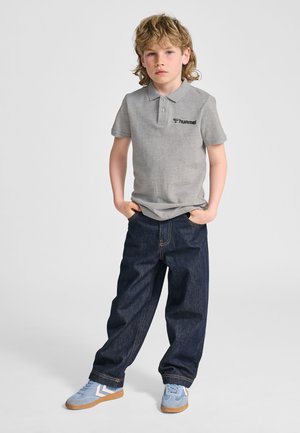 Grå polo t-shirt med to knapper og sort logo, kombineret med mørkeblå denimjeans og lyseblå sneakers med hvide detaljer.