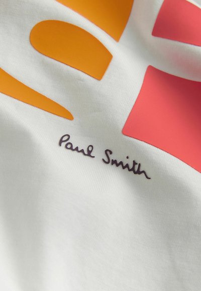 Bílá bavlněná tričko s velkými oranžovými a růžovými grafickými tvary. Obsahuje podpis "Paul Smith" v tmavě fialové barvě v dolním levém rohu.