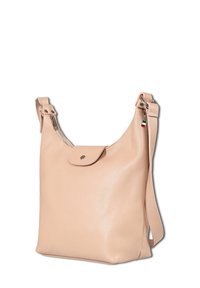 Beige leren schoudertas met een flap met drukknoop aan de voorkant, ritssluitingen, een verstelbare schouderband en een klein Italiaans vlaggetje, op een witte achtergrond.