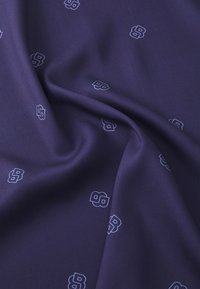Námorná látka s hladkou textúrou s opakujúcim sa svetlomodrým vzorom loga. Dizajn je jemný a rovnomerne rozložený po povrchu.