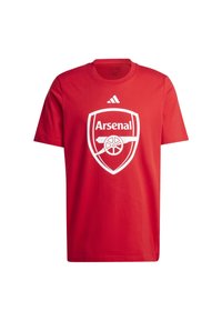 Červené bavlnené tričko s bielym logom Arsenal uprostred, s logom adidas nad ním. Okrúhly výstrih, krátke rukávy, štandardné strih.