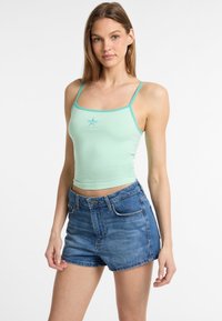 Top cropped verde menta con spalline sottili e accenti turchesi, abbinato a pantaloni corti in denim blu a vita alta, con tasche frontali.