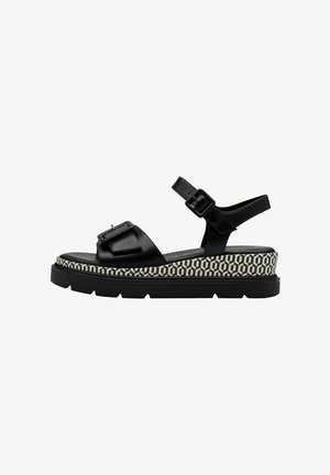 Zwarte leren platform sandalen met verstelbare gespsluitingen, voorzien van een gestructureerde wit- en zwartgepatroneerde zool.