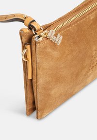 Beige suède clutch met een gouden rits, een gestructureerd oppervlak en een gedraaide leren handgreep. Kleine decoratieve kralen versieren de rits.
