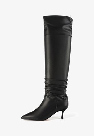 Mustmust mustekad kengad, millel on lõdva disain, terav varvas ja peen konts. Sile tekstuur ja voolujooneline, minimalistlik profiil.