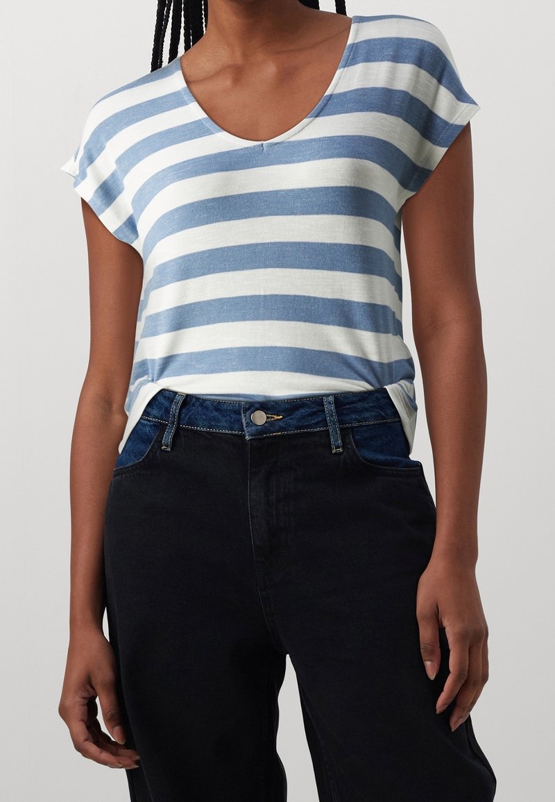 Striped t-shirt in light blue and white, featuring a v-neck and short sleeves, paired with high-waisted dark jeans with a button closure.