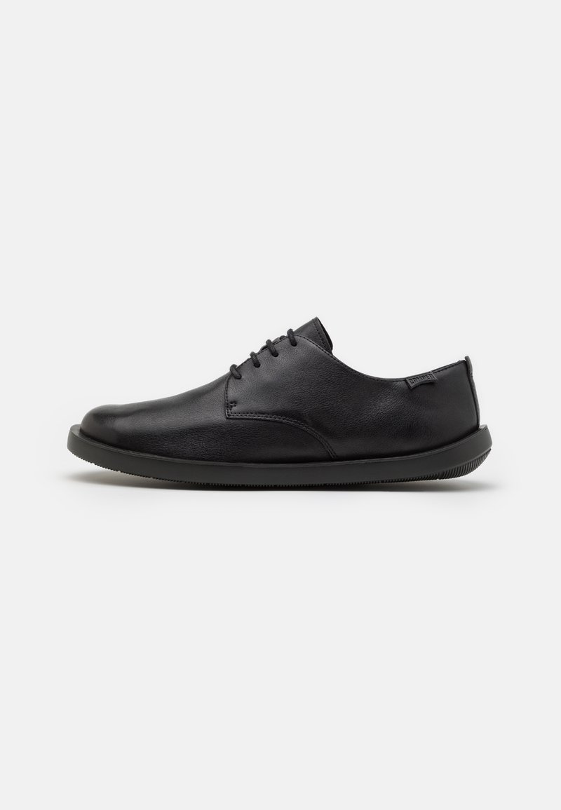 Chaussure habillée en cuir noir à lacets, bout rond et semelle plate, vue de profil sur fond blanc.