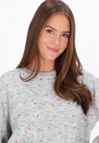 Grijze sweater van een textuurstof, met multicolore stippen en een geribde ronde halslijn. Zacht materiaal en een relaxte pasvorm.