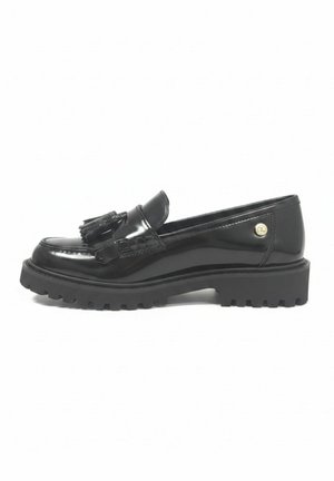 Zwarte glanzende leren loafer met kwastjes, dikke profielzool en klein rond goudkleurig embleem aan de zijkant, bekeken vanaf de buitenkant.