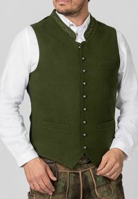 Grüner Wollweste mit hohem Kragen, silbernen Knöpfen, zwei vorderen Taschen und kunstvollen Stickereien am Ausschnitt.