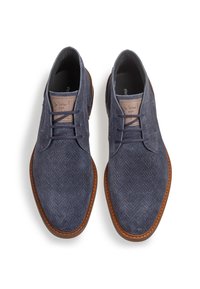 Zapatos de tela azul marino con un patrón de espiga, detalles en cuero, cordones redondos y suela de goma marrón. Diseño plano y de perfil bajo.