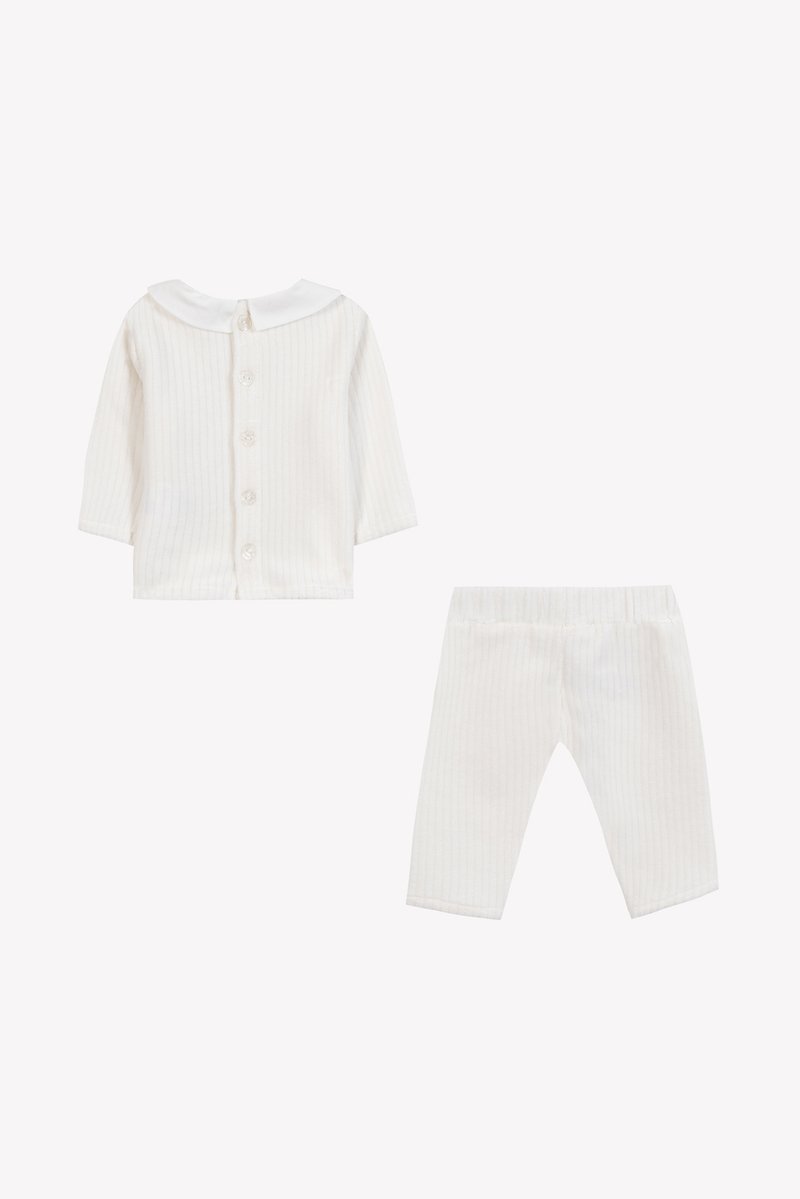 Ensemble pour nourrisson en blanc à côtes, comprenant un haut à col et manches longues avec fermeture par boutons et un pantalon à taille élastique assorti. Texture douce.