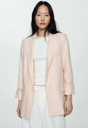 Light pink blazer with tailored fit, notched lapels, and rolled-up sleeves. Worn over a white top, with a smooth, textured fabric.