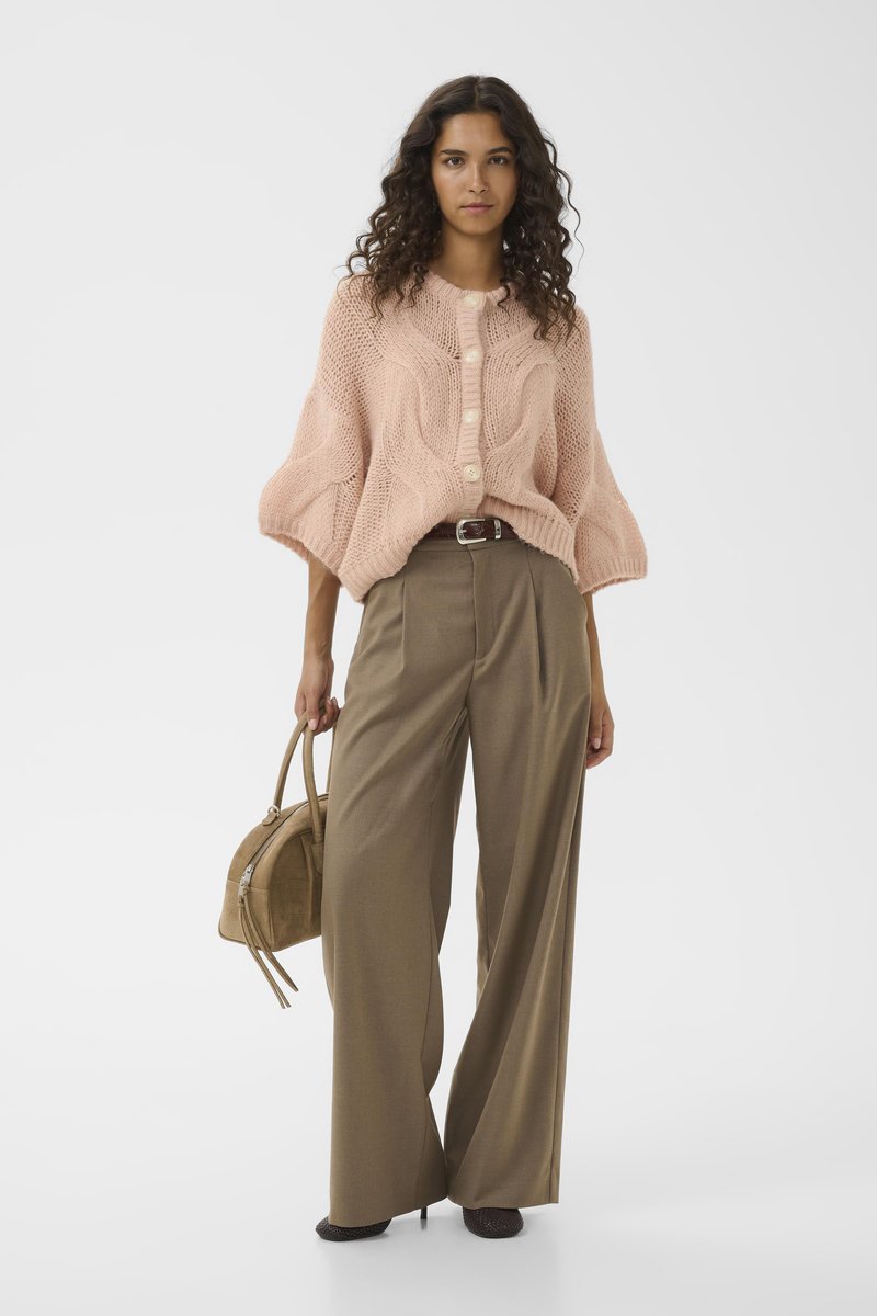 Overmaat blush gebreide trui met een textuurpatroon en knopen, gecombineerd met high-waisted bruine wijde broek en een tan handtas.