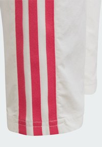 Witte sportbroek met twee verticale roze strepen. Gewoven stof met contrasterende witte strepen. Zoom afgewerkt met een nette, gestikte rand.