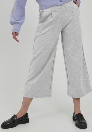 Grijze, cropped, wijde broek gemaakt van zachte, gemêleerde stof, met voorplooien en zijzakken. Gepaarde met zwarte loafers.