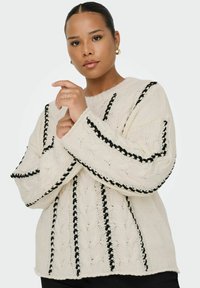 Pull en laine blanche avec des coutures en relief noires et des détails d'accent. Manches larges et col rond, avec un design texturé.