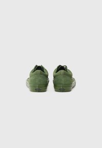 Zapatillas de ante verde con un diseño de perfil bajo, que cuentan con respaldos redondeados, suelas de goma y detalles de costura blanca en contraste.