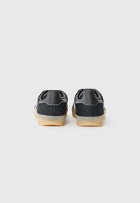 Twee paar zwarte sportschoenen met textuurstof, gezien vanaf de achterkant, tegen een effen witte achtergrond.