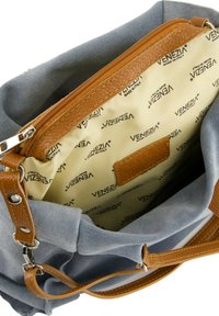 Grå ruskinds håndtaske med brune læderdetaljer; indvendig foret med beige stof med gentagne "Venezia" logoer. Lynlåslomme synlig.