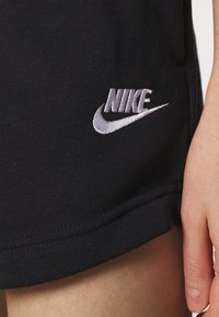 Svarta bomullsshorts med en broderad vit Nike-logotyp. Tyget verkar mjukt med en fållkant och en lätt stretch.