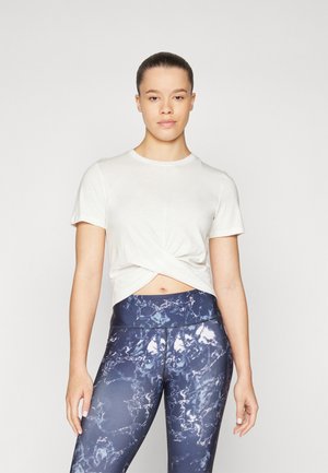 Knot-front white t-shirt paired with blue marble-pattern leggings. Both garments display a soft texture and fitted design.