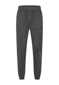 Pantalons de survêtement gris en tissu doux, dotés d'une taille élastique avec cordons de serrage et de deux poches latérales ; grand logo noir imprimé sur une jambe.