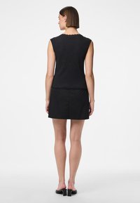 Svart ermeløs topp med bølget halslinje, kombinert med en svart tettsittende skjørt, som viser glatt stoff og et minimalistisk design.