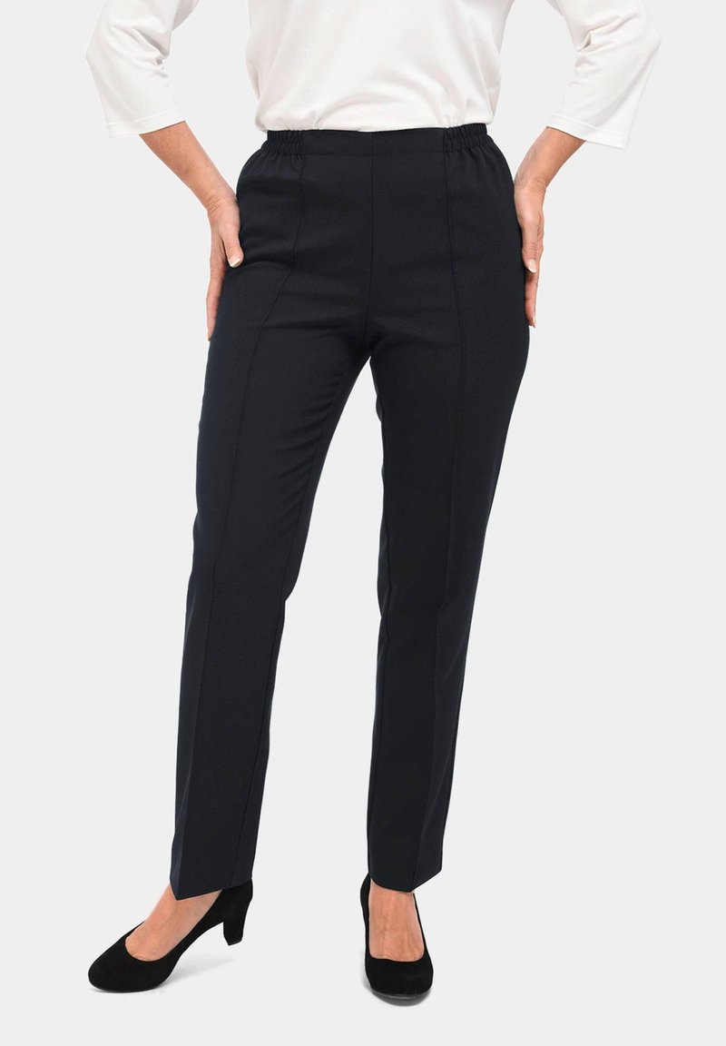 Zwarte, rekbare stoffen broek met een elastische tailleband, recht gesneden pijpen en naden aan de zijkant. Gemaakt met zwarte hakken.