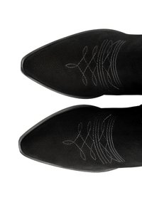 Czarne zamszowe buty kowbojskie z ostrymi noskami, zdobione dekoracyjnymi białymi strojami na górnej części. Gładka struktura przez cały czas.